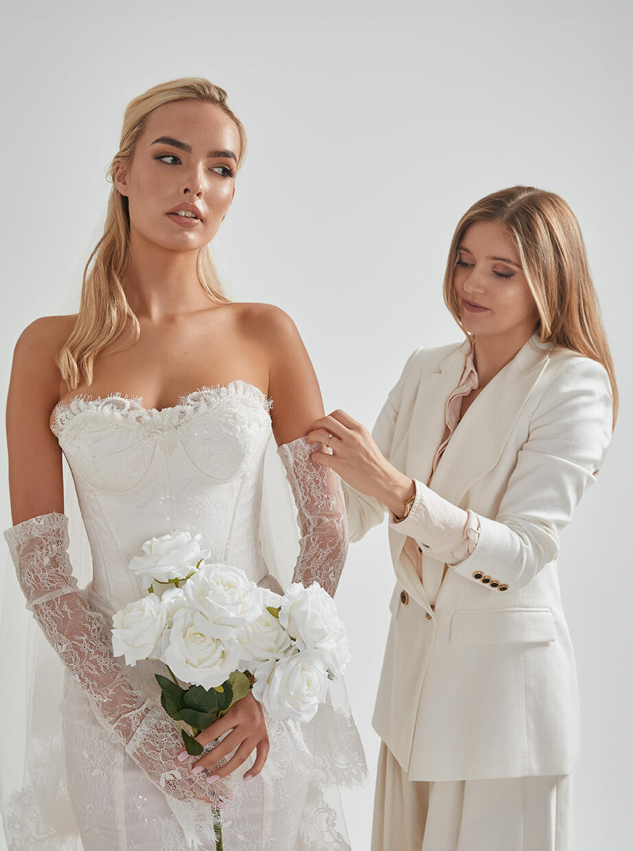 AM Bridal Studio specialist making final adjustments to a bride’s wedding gown during her fitting.